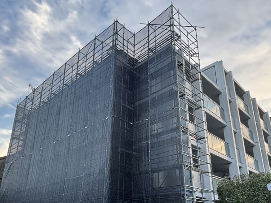 メッシュシートで囲った外壁改修工事中の建物